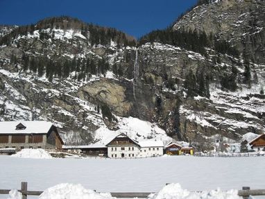 Gasthof in den Bergen mit Wasserfall im Winter mit Schnee