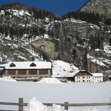 Gasthof in den Bergen mit Wasserfall im Winter mit Schnee