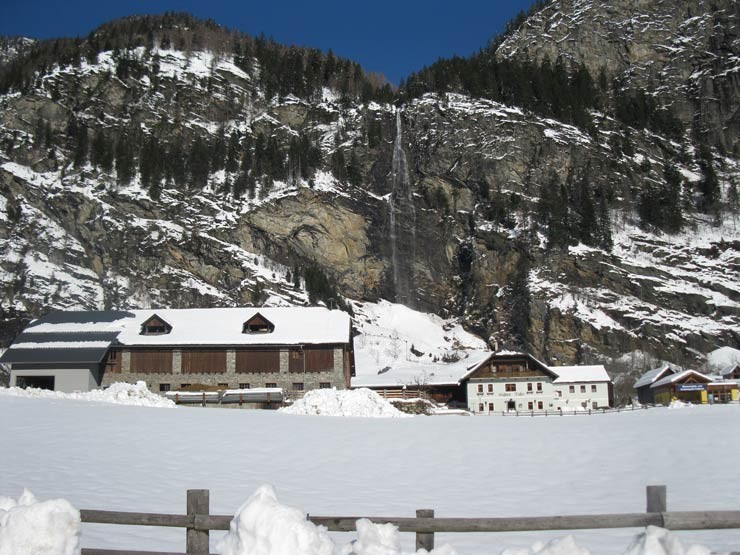 Gasthof in den Bergen mit Wasserfall im Winter mit Schnee